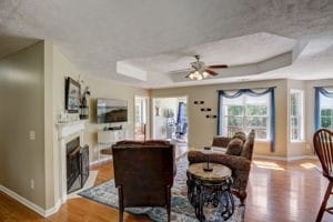 living room featuring ceiling fan, a raised ceiling, and hardwood / wood-style flooring