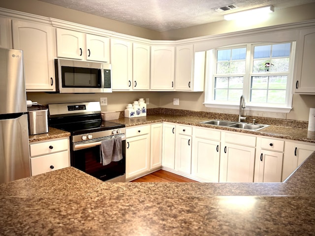 kitchen with white cabinetry, stainless steel appliances, sink, and light hardwood / wood-style floors