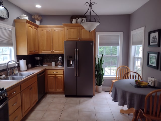 kitchen with light tile patterned floors, plenty of natural light, sink, black appliances, and decorative backsplash