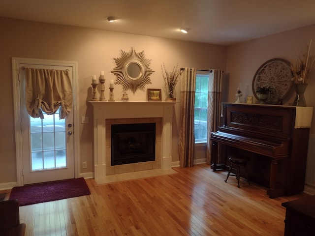 living room with a tile fireplace, a healthy amount of sunlight, and light hardwood / wood-style floors