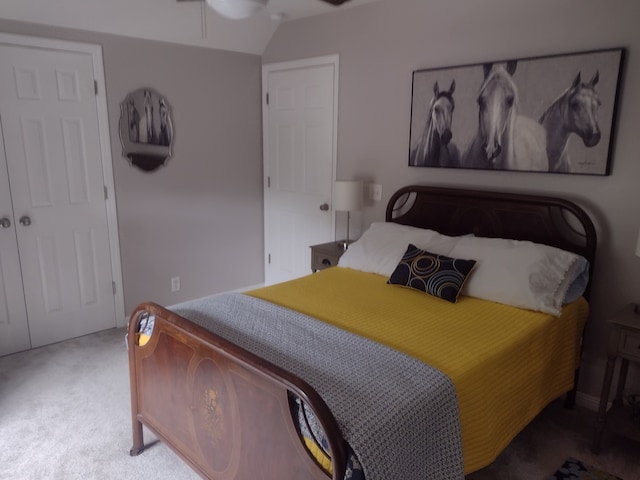 carpeted bedroom with ceiling fan, a closet, and vaulted ceiling