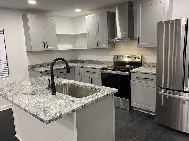 kitchen featuring light stone countertops, stainless steel appliances, a kitchen island with sink, sink, and wall chimney range hood