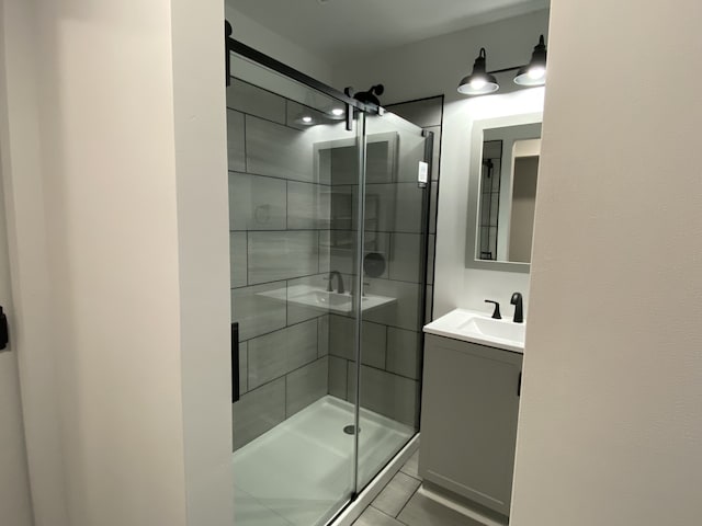 bathroom with tile patterned flooring, vanity, and walk in shower