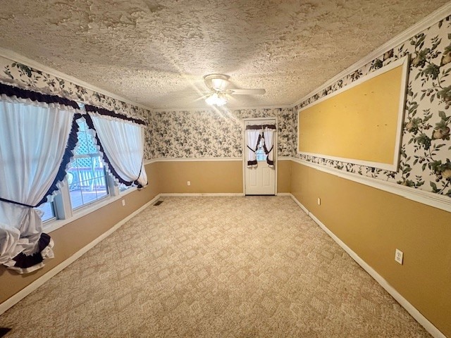 carpeted empty room featuring ceiling fan, crown molding, and a textured ceiling