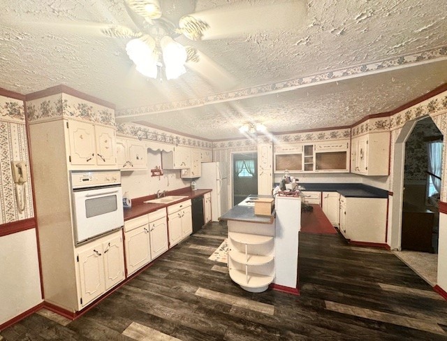 kitchen featuring dark wood-type flooring, sink, a textured ceiling, and white oven