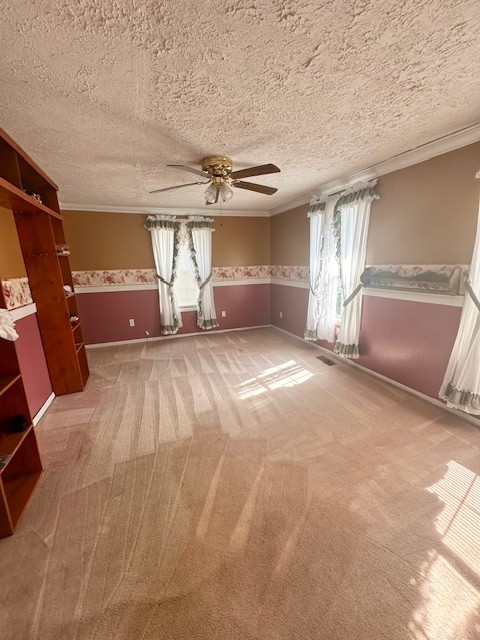 carpeted empty room with a textured ceiling, plenty of natural light, and crown molding