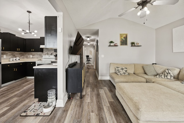 living room featuring hardwood / wood-style floors, ceiling fan with notable chandelier, and vaulted ceiling