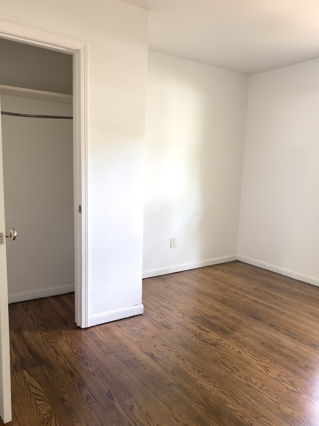 unfurnished bedroom with a closet and dark hardwood / wood-style flooring