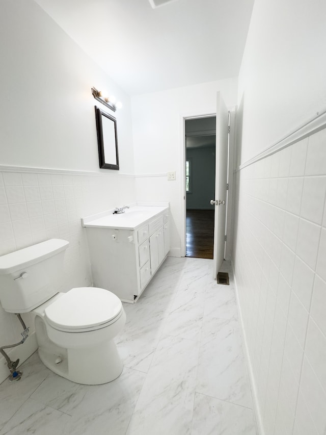 bathroom featuring tile walls, toilet, hardwood / wood-style flooring, and vanity