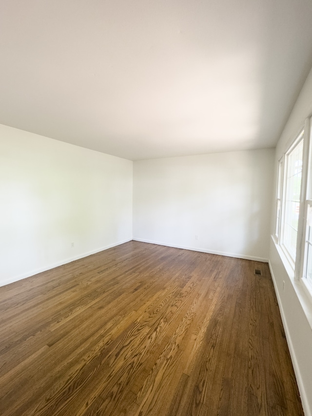 spare room with hardwood / wood-style flooring and vaulted ceiling