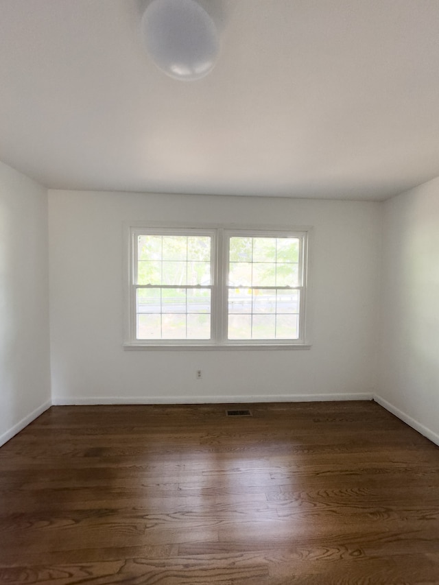 spare room with a wealth of natural light and dark hardwood / wood-style flooring