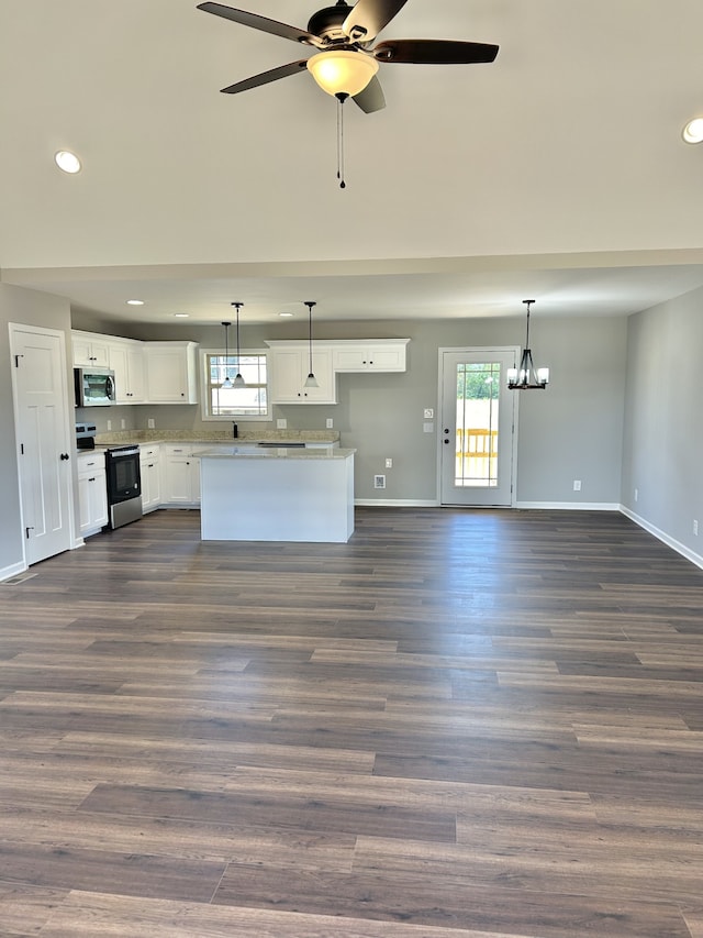 unfurnished living room with ceiling fan with notable chandelier, dark hardwood / wood-style flooring, and plenty of natural light