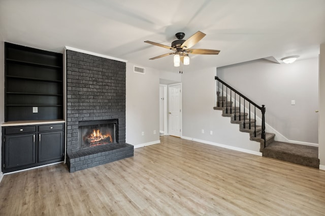 unfurnished living room featuring ceiling fan, light wood-type flooring, and a fireplace