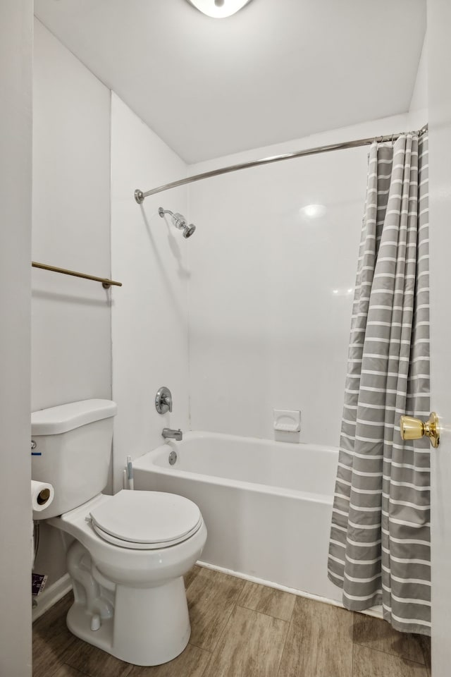 bathroom featuring shower / bathtub combination with curtain, hardwood / wood-style flooring, and toilet