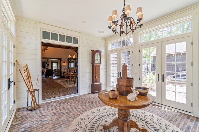 doorway to outside featuring wood walls, french doors, and an inviting chandelier