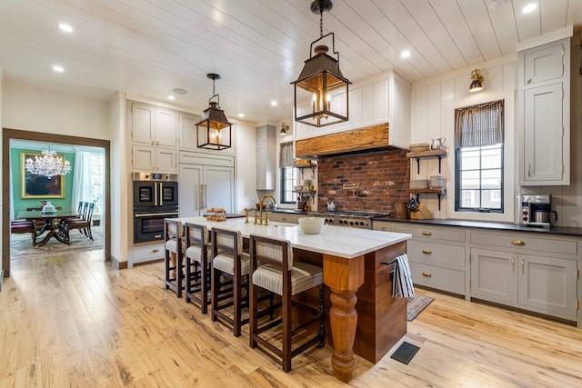 kitchen featuring paneled fridge, a wealth of natural light, hanging light fixtures, and light hardwood / wood-style floors