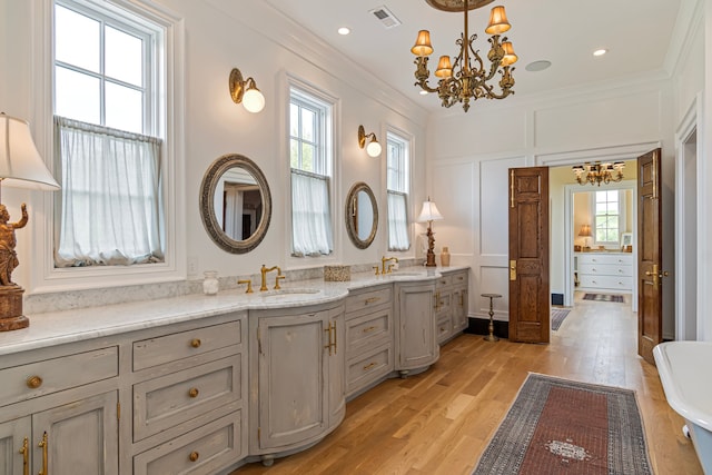 bathroom with a bath, a healthy amount of sunlight, ornamental molding, and hardwood / wood-style flooring