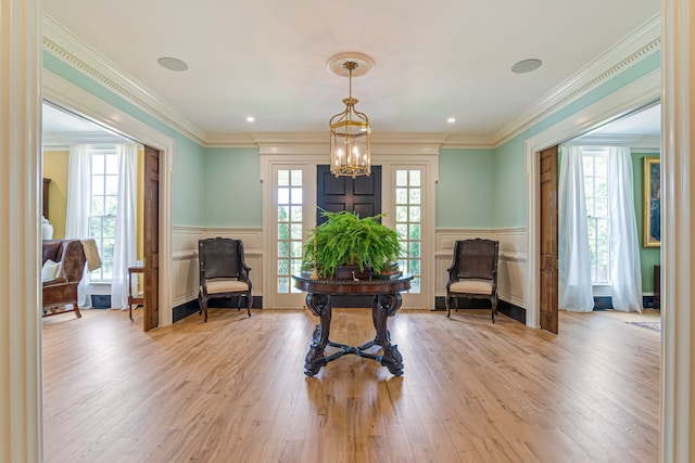 living area featuring light hardwood / wood-style flooring, a chandelier, and ornamental molding