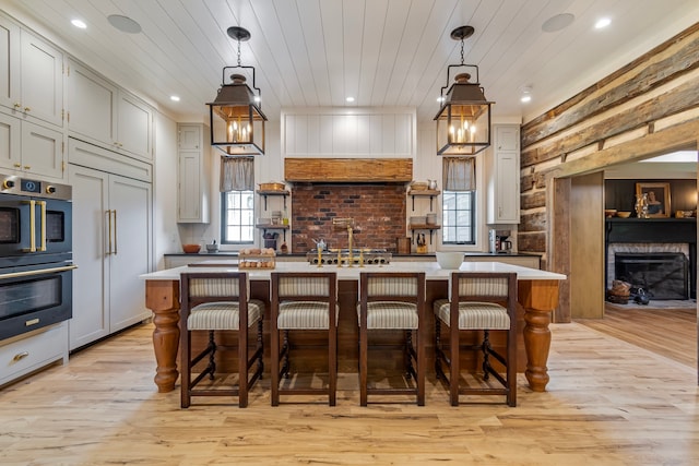 kitchen with a center island with sink, pendant lighting, a kitchen bar, and light hardwood / wood-style floors