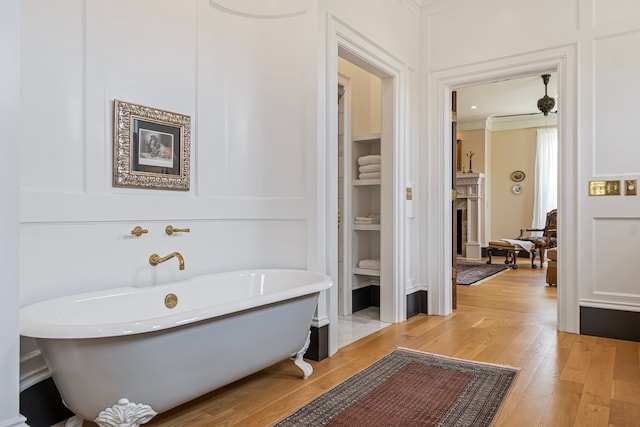 bathroom with hardwood / wood-style floors, ornamental molding, and a washtub