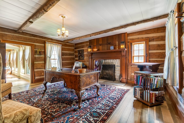 home office with a notable chandelier, wood walls, beamed ceiling, and light hardwood / wood-style floors