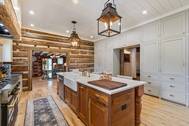 kitchen featuring appliances with stainless steel finishes, a center island with sink, sink, light hardwood / wood-style floors, and rustic walls