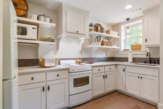 kitchen with light hardwood / wood-style flooring, white cabinetry, hanging light fixtures, white appliances, and sink