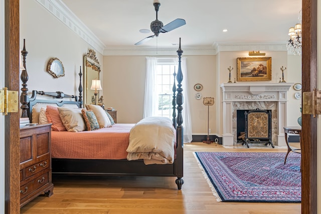 bedroom featuring hardwood / wood-style floors, a fireplace, ornamental molding, and ceiling fan