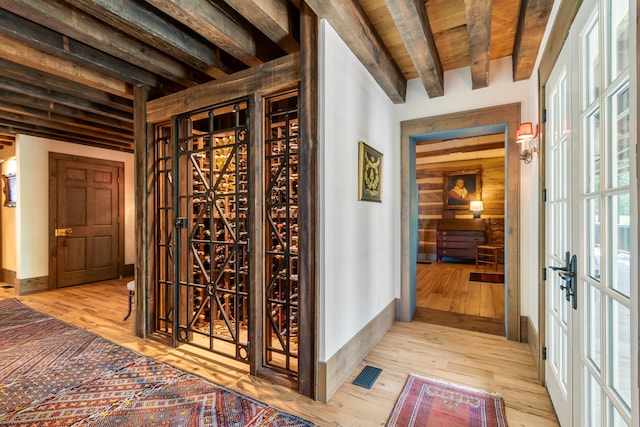 wine room featuring light hardwood / wood-style flooring, beamed ceiling, and wood ceiling