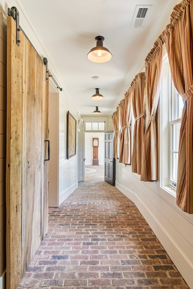 hall featuring a barn door and a healthy amount of sunlight