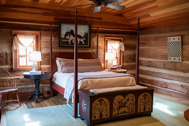 bedroom featuring lofted ceiling, wood ceiling, hardwood / wood-style floors, ceiling fan, and wood walls