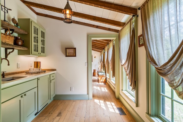 interior space with lofted ceiling with beams, light wood-type flooring, sink, and green cabinetry