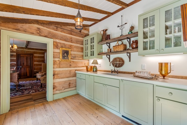 kitchen featuring lofted ceiling with beams, wooden walls, decorative light fixtures, light wood-type flooring, and green cabinets