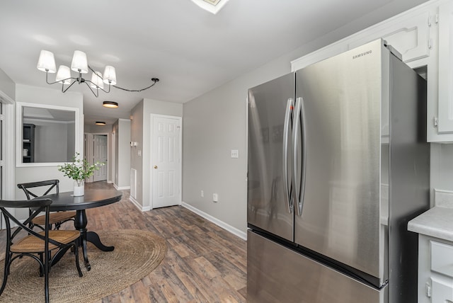 kitchen with white cabinetry, stainless steel fridge, dark hardwood / wood-style flooring, and a chandelier