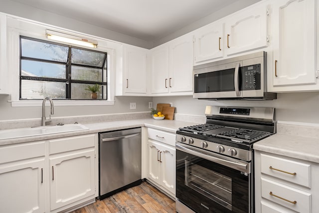 kitchen with white cabinetry, sink, light hardwood / wood-style flooring, and appliances with stainless steel finishes