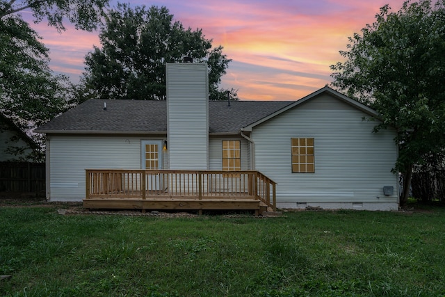 back house at dusk with a yard and a deck