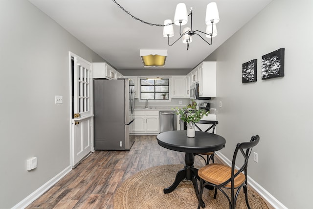 kitchen featuring sink, dark hardwood / wood-style floors, appliances with stainless steel finishes, white cabinetry, and a chandelier