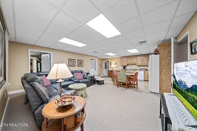 living area with baseboards, visible vents, and a drop ceiling