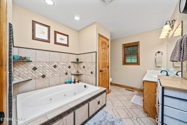 full bath with toilet, vanity, baseboards, tile patterned floors, and a whirlpool tub