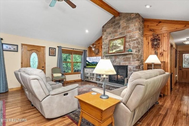 living area with vaulted ceiling with beams, a fireplace, wood finished floors, a ceiling fan, and baseboards