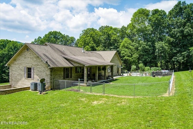 back of house with cooling unit and a yard