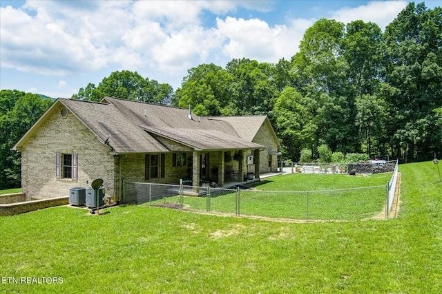 back of property featuring a fenced backyard, cooling unit, and a lawn