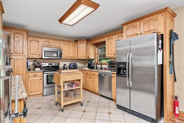 kitchen with stainless steel appliances, light countertops, and light brown cabinetry