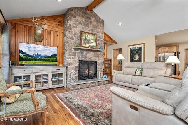 living room featuring high vaulted ceiling, a stone fireplace, light wood-style flooring, wood walls, and beamed ceiling