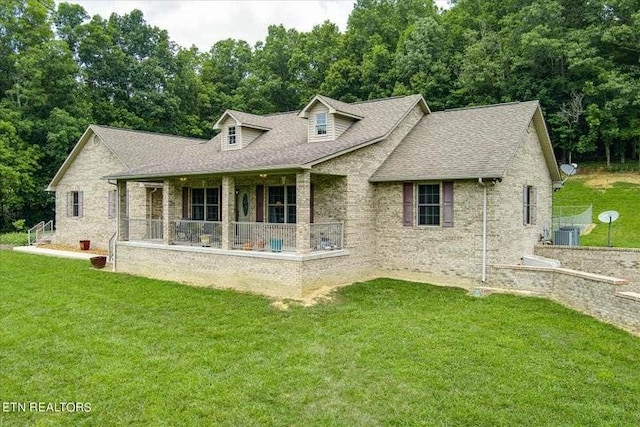 rear view of property featuring a shingled roof, covered porch, a yard, and central air condition unit