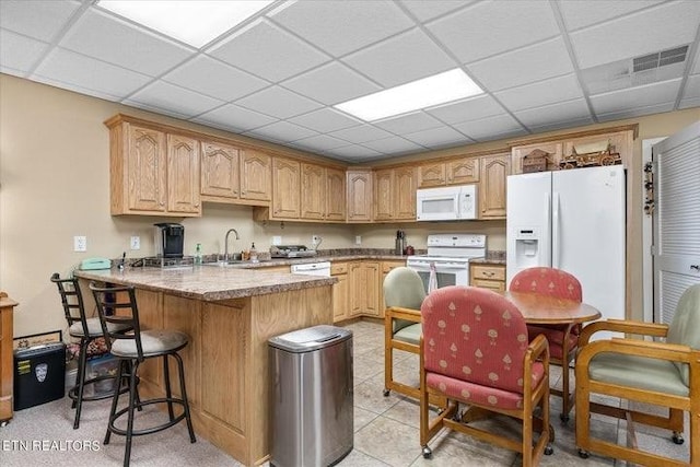 kitchen featuring stone counters, a paneled ceiling, white appliances, a sink, and visible vents