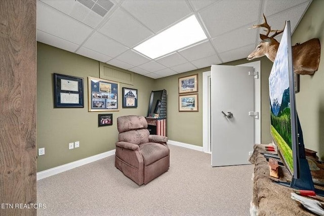 living area with a paneled ceiling, baseboards, and carpet