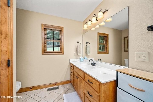 bathroom featuring visible vents, toilet, vanity, baseboards, and tile patterned floors