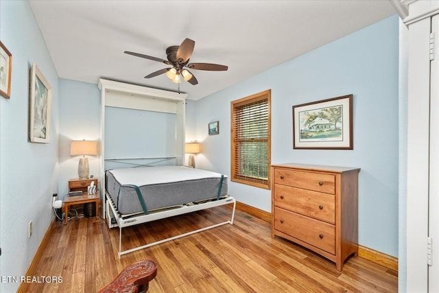 bedroom featuring ceiling fan, light wood-style flooring, and baseboards