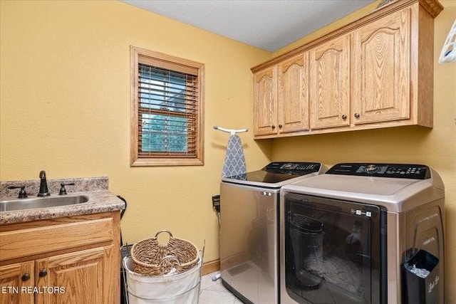 washroom with cabinet space, light tile patterned floors, baseboards, washer and dryer, and a sink